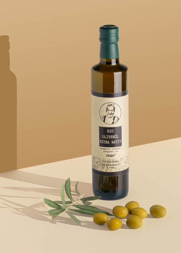 Bio Olivenöl von Aimilios Organics auf braunem Hintergrund mit Oliven als Deko